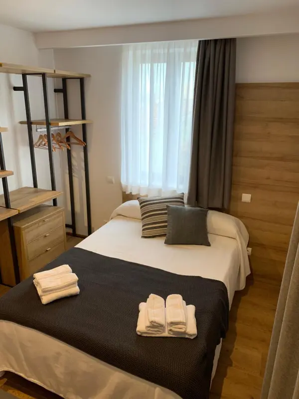 Une chambre avec un lit simple et un portant à vêtements.