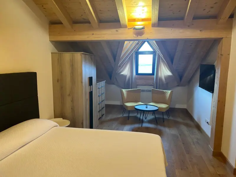 Une chambre mansardée lumineuse avec un lit et un coin salon.