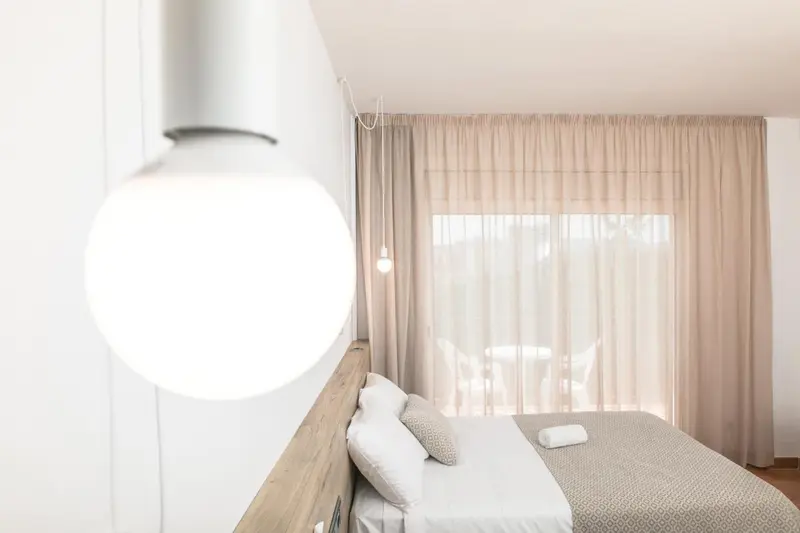 Une chambre lumineuse avec un lit et une fenêtre drapée.