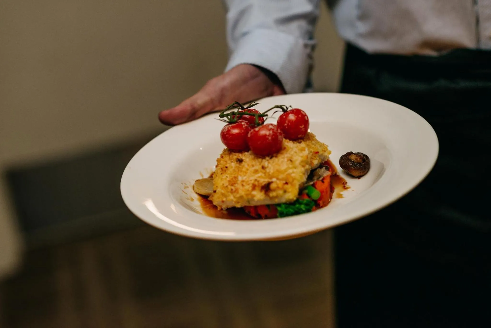Une assiette de poisson est présentée par une main.