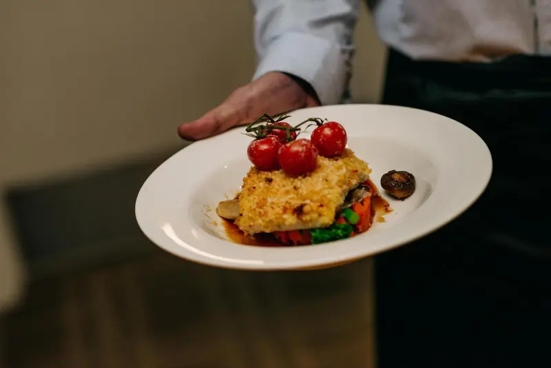 Une assiette de poisson est présentée par une main.
