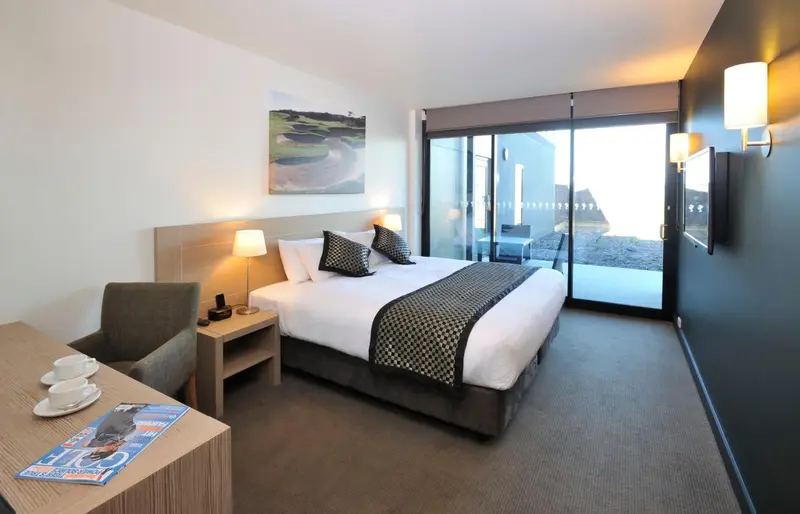 Chambre moderne avec un grand lit et un accès à une terrasse ensoleillée.