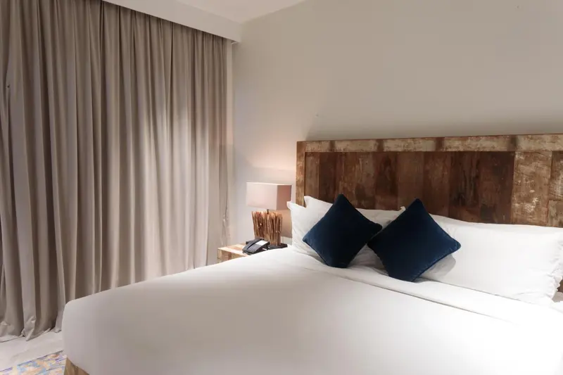Une chambre lumineuse avec un grand lit recouvert de coussins bleus.