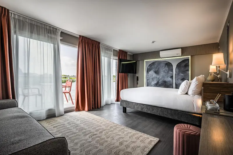 Chambre moderne avec un grand lit et un accès à un balcon.
