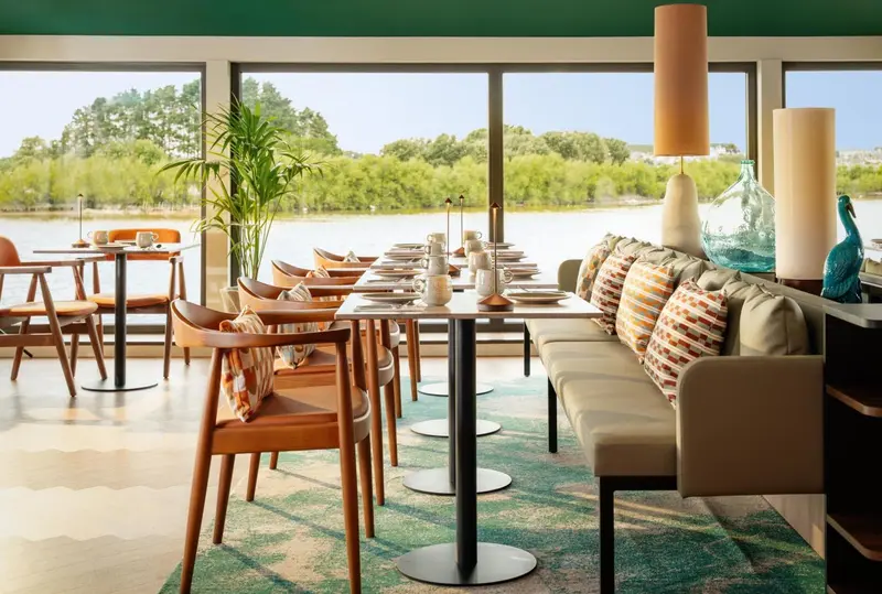 Une salle à manger lumineuse avec des tables dressées et un coin salon confortable.