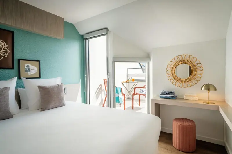 Une chambre lumineuse avec un lit double et un coin bureau.