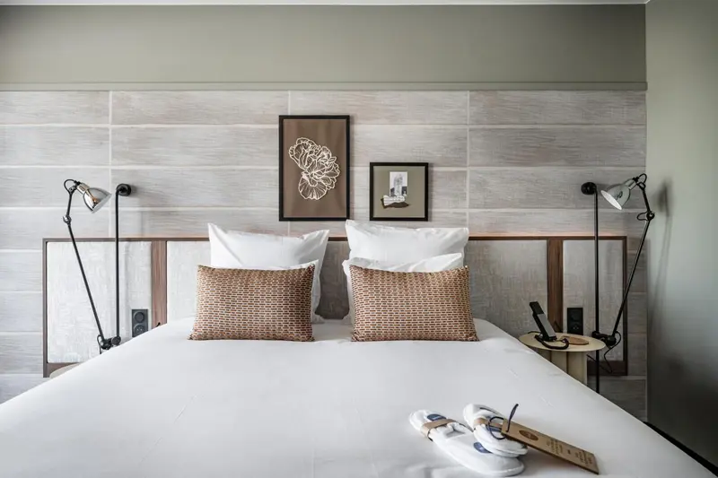 Un lit double avec oreillers blancs et coussins décoratifs dans une chambre moderne.