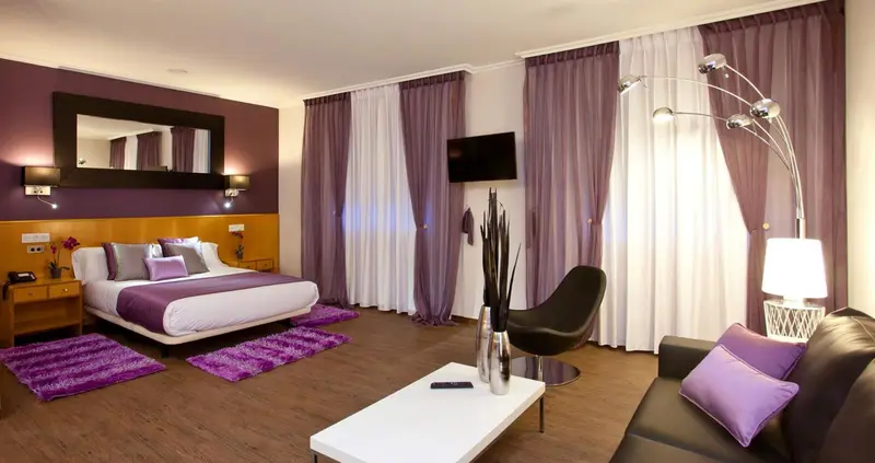Une chambre moderne avec un lit double, un canapé et une décoration violette.