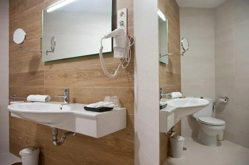 Deux vasques blanches et un toilette dans une salle de bain moderne.