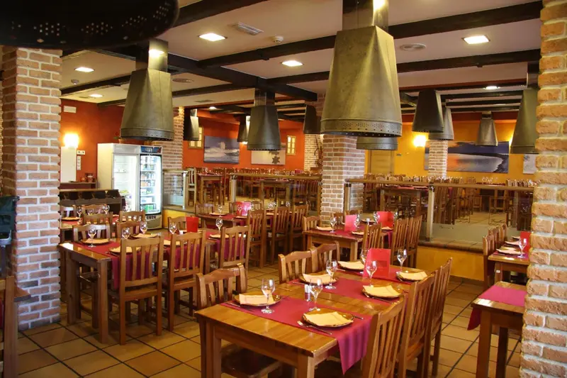 Une salle de restaurant avec des tables dressées et des suspensions métalliques.