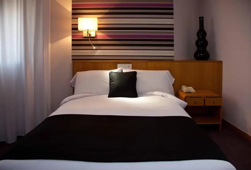 Une chambre avec un lit recouvert d'une couverture noire et de coussins.