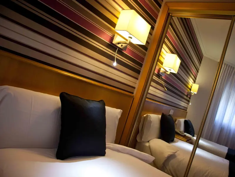 Un lit avec oreillers et coussin noir dans une chambre décorée de rayures.