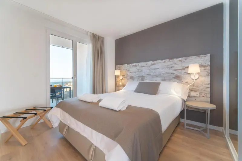 Une chambre lumineuse avec un grand lit et un accès à un balcon.