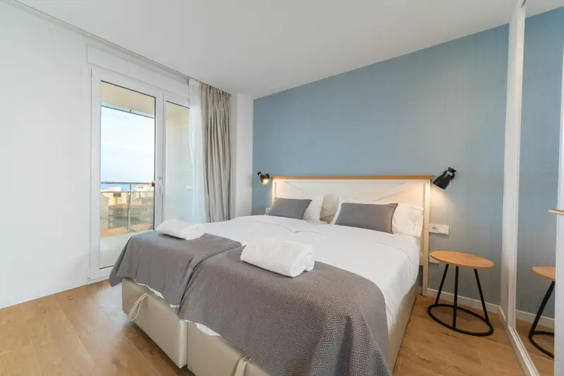 Une chambre lumineuse avec un grand lit et un accès à un balcon.