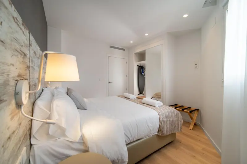 Une chambre lumineuse avec un grand lit recouvert de linge blanc.