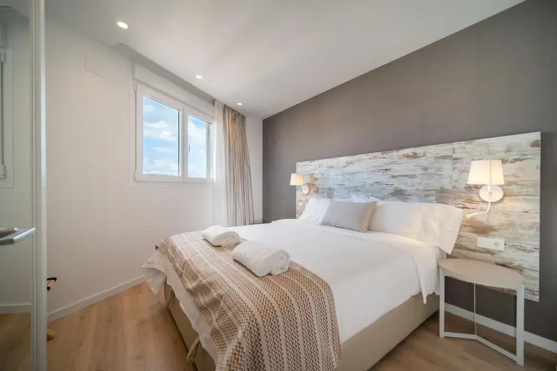 Une chambre lumineuse avec un grand lit et une tête de lit en bois clair.