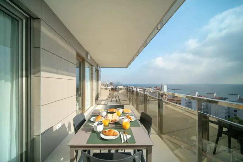Une table est dressée pour le petit-déjeuner sur un balcon avec vue sur la mer.