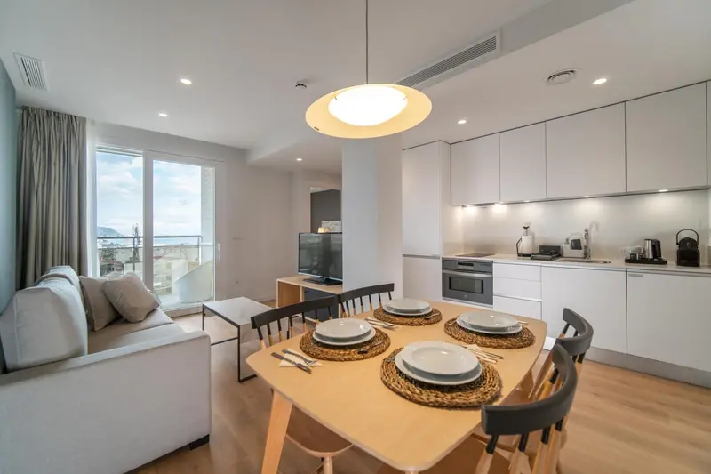 Espace de vie lumineux avec cuisine équipée et table à manger près d'une fenêtre.