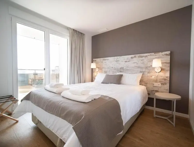 Une chambre lumineuse avec un grand lit et un accès à un balcon.