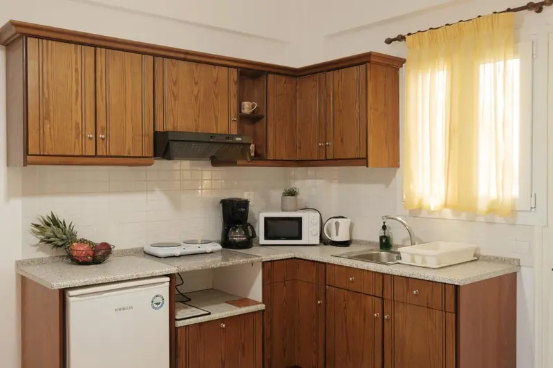 Une kitchenette lumineuse avec des placards en bois et un plan de travail.