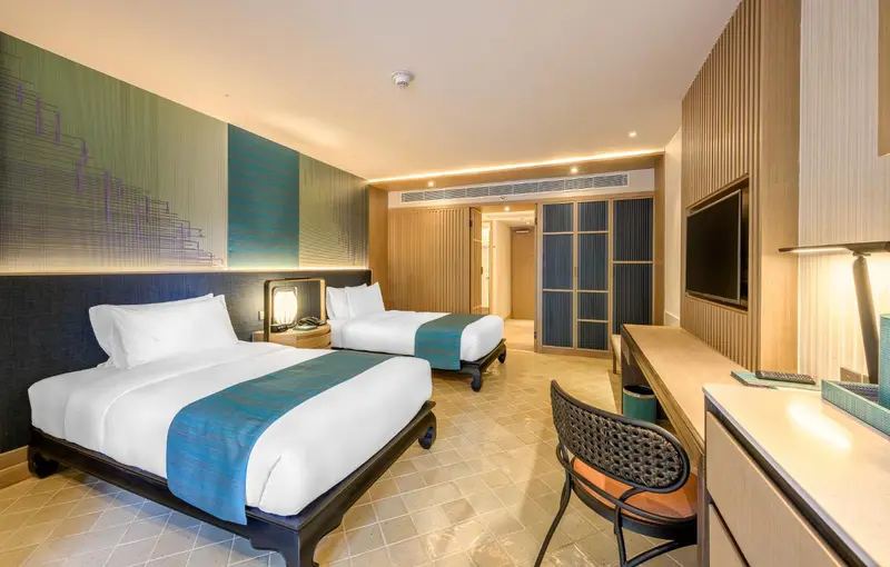 Chambre d'hôtel moderne avec deux lits simples et un bureau.