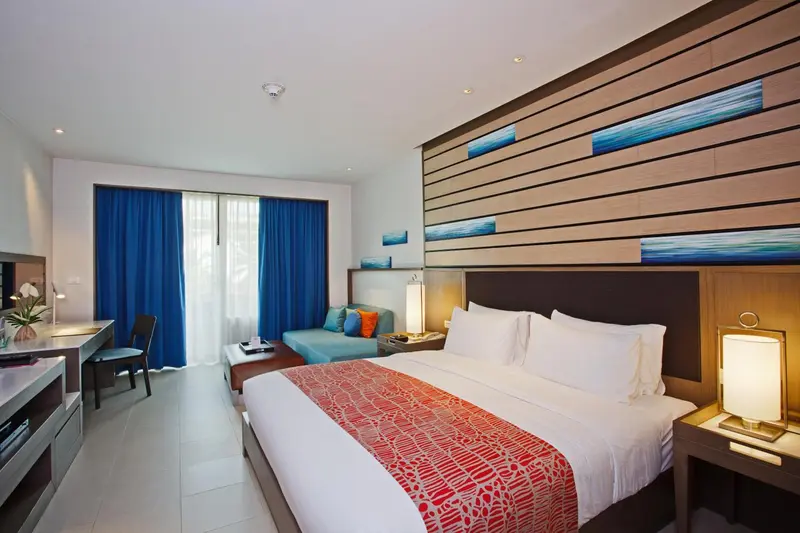 Une chambre lumineuse avec un grand lit recouvert d'une courtepointe colorée.