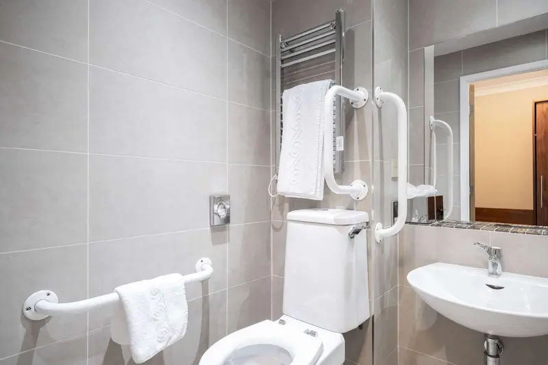 Une salle de bain moderne avec des carreaux gris et des accessoires chromes.