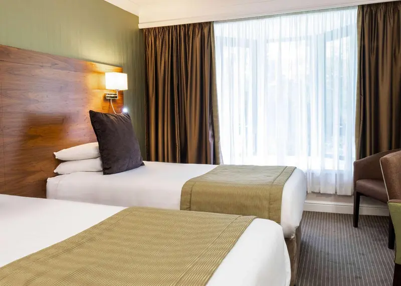 Une chambre d'hôtel avec deux lits simples et une fenêtre.