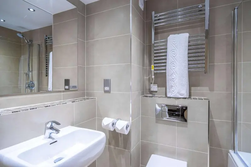 Une salle de bain moderne avec carrelage beige et équipements sanitaires blancs.