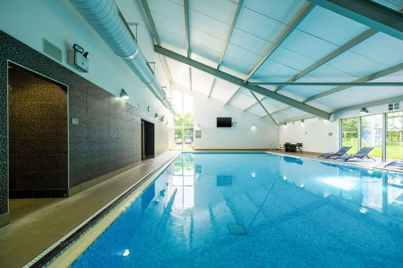 Une piscine intérieure lumineuse avec des transats au bord.