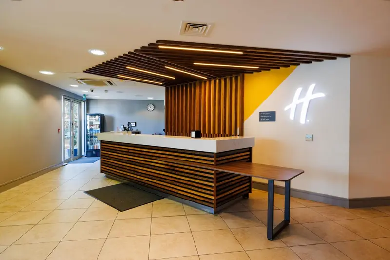 Hall d'accueil moderne avec un comptoir en bois et un éclairage suspendu.