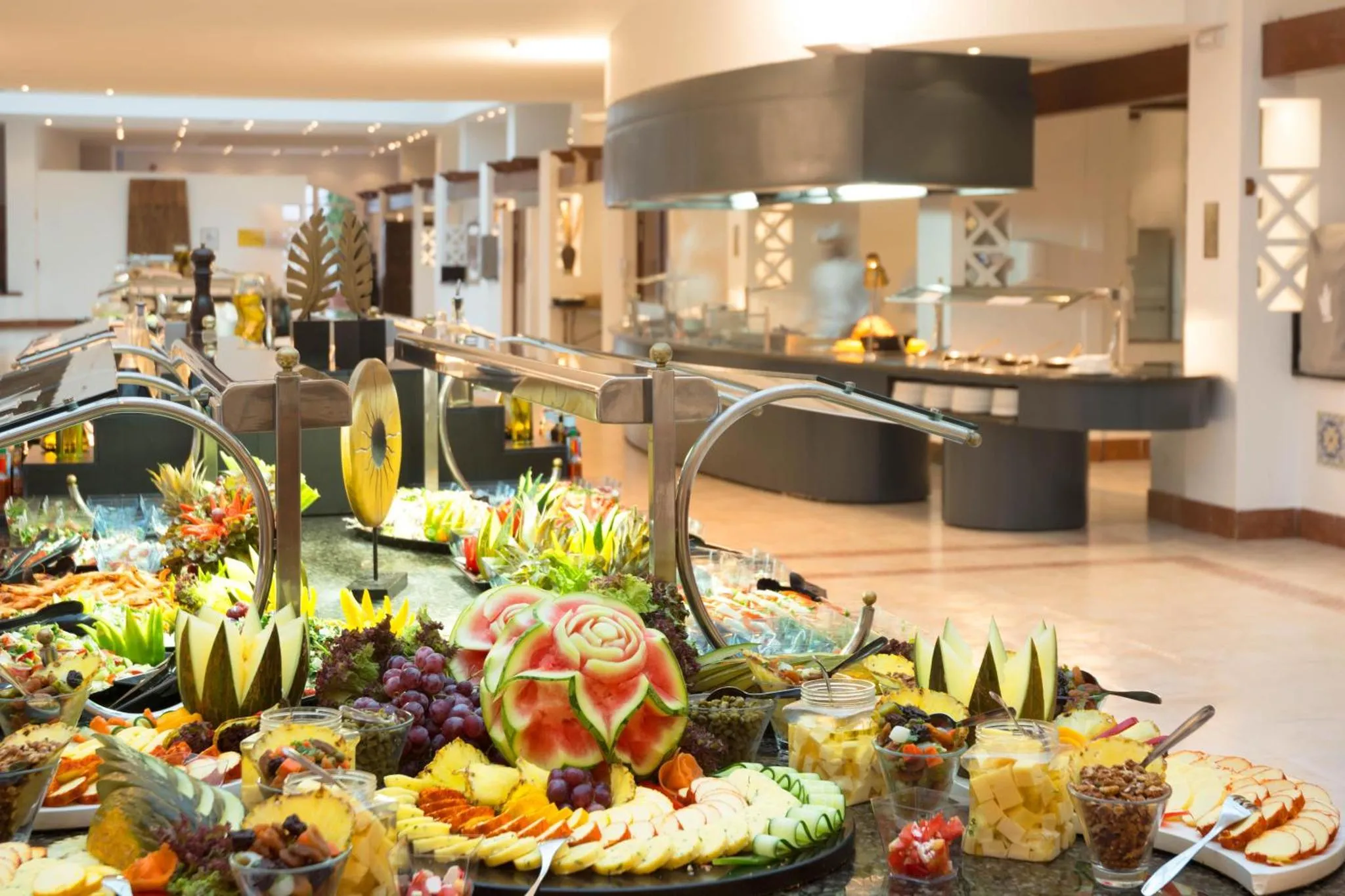 Un buffet généreux propose une variété de plats et de fruits frais dans une salle lumineuse.