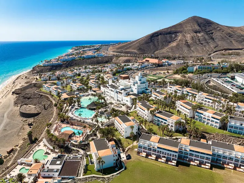 Vue aérienne d'un complexe hôtelier au bord de la mer et d'une montagne.