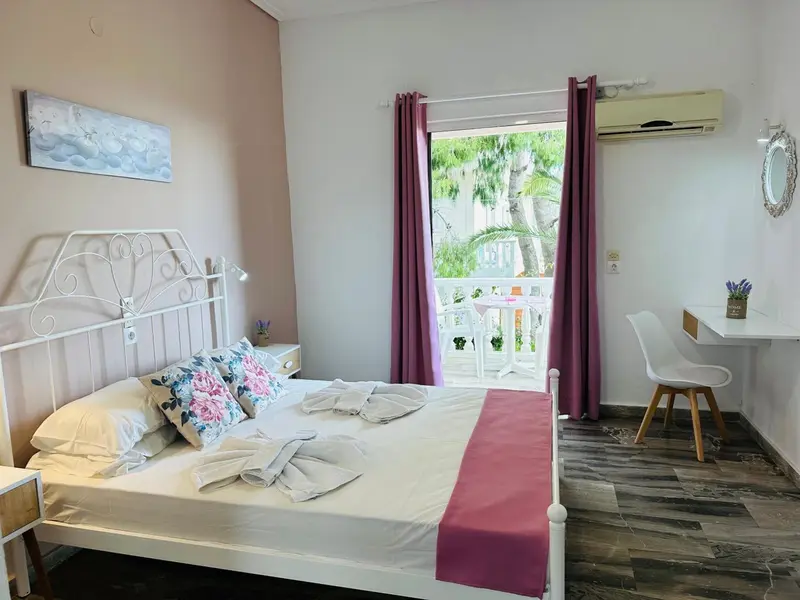 Une chambre lumineuse avec un lit blanc et un bureau près d'une fenêtre.