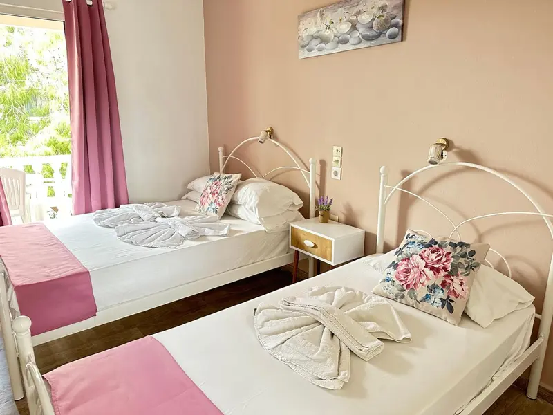 Chambre lumineuse avec deux lits simples et décoration florale.