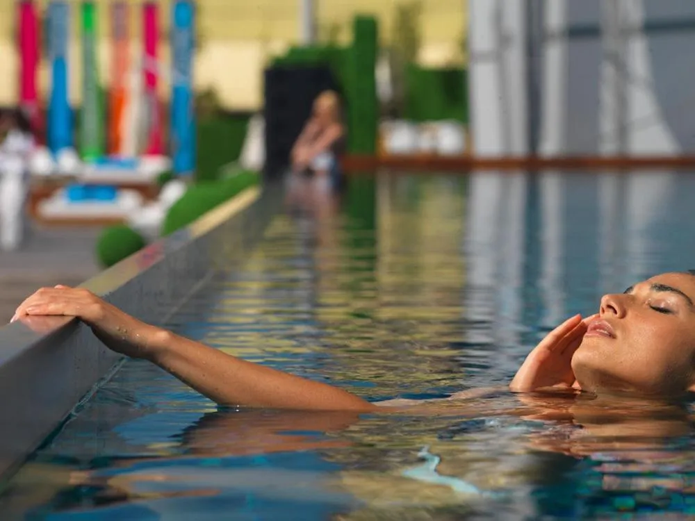Une femme se détend dans une piscine bordée d'une terrasse.