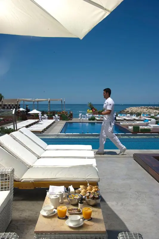 Transats blancs disposés autour d'une piscine avec un serveur en mouvement.