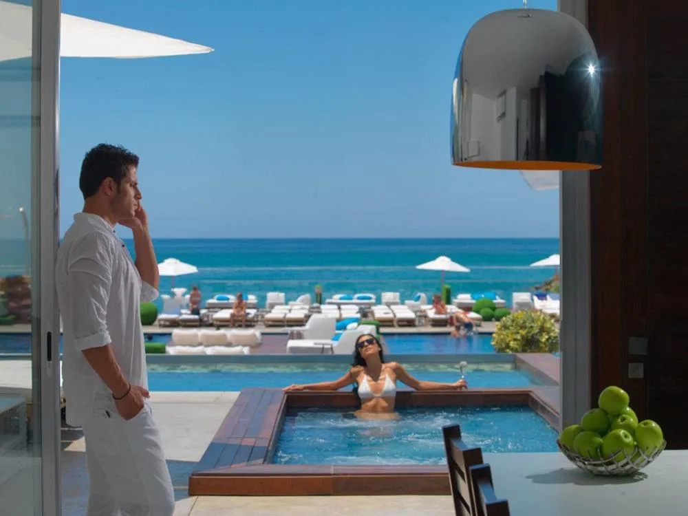 Un homme et une femme se détendent près d'une piscine avec vue sur la mer.