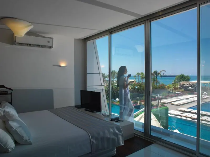 Une chambre lumineuse donne sur une piscine et la mer.