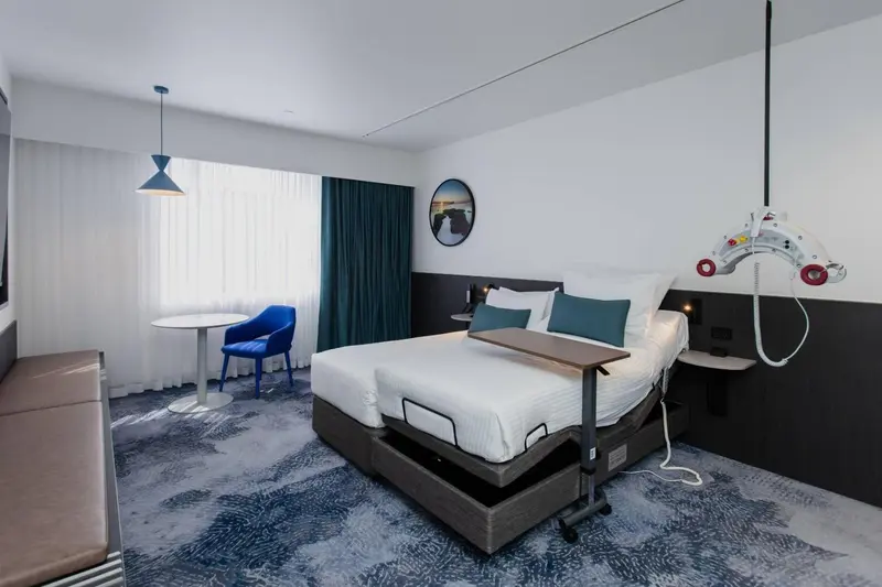 Une chambre moderne avec un grand lit et un fauteuil bleu.