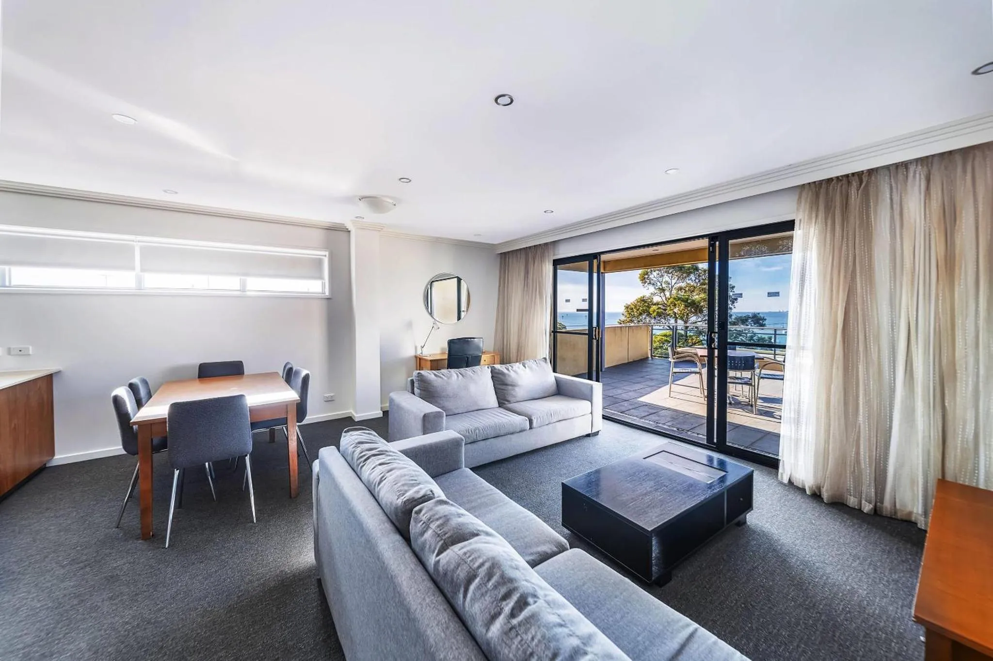 Un salon lumineux s'ouvre sur une terrasse avec vue sur la mer.