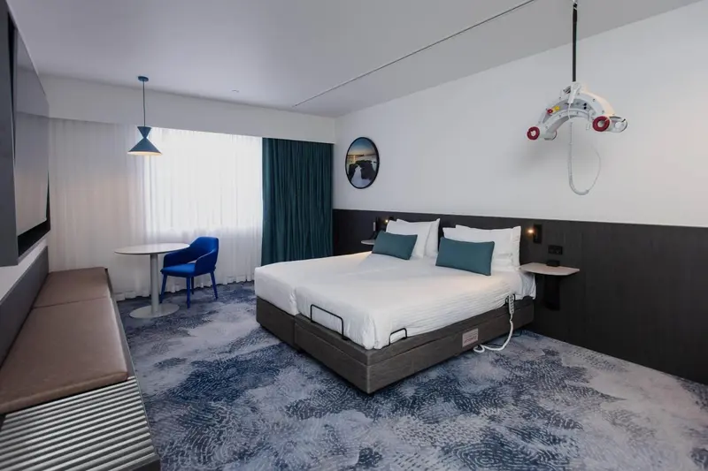 Chambre lumineuse avec un grand lit et un coin salon.
