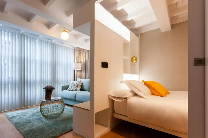 Une chambre lumineuse avec un canapé bleu et un lit simple.
