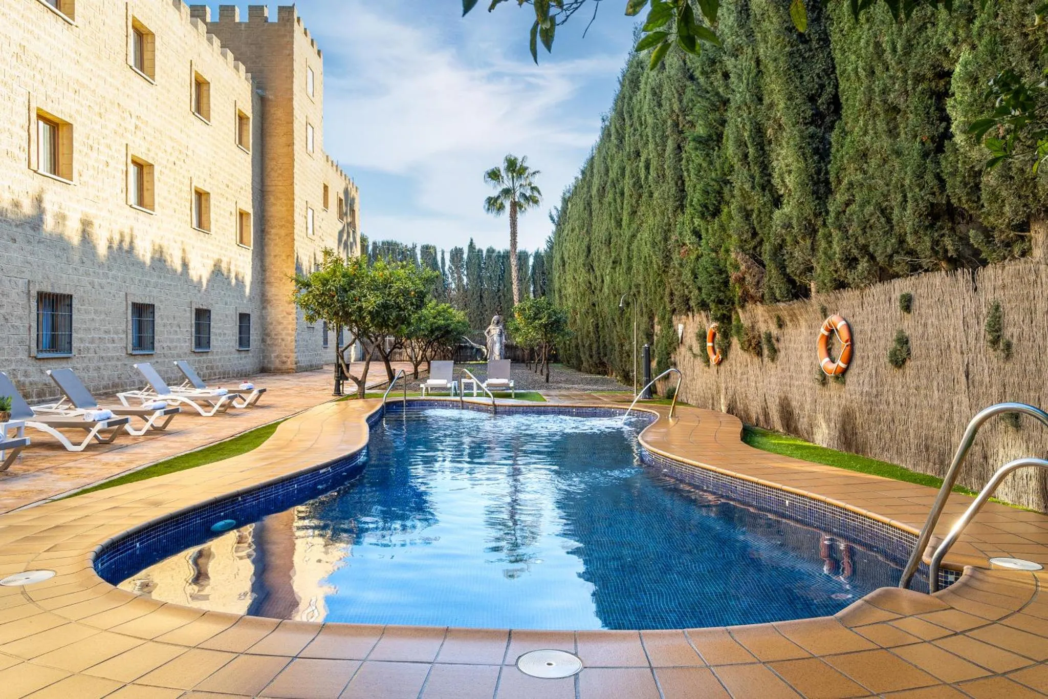 Une piscine rectangulaire avec des transats et une végétation luxuriante.