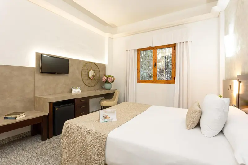 Une chambre lumineuse avec un lit confortable et un espace bureau.