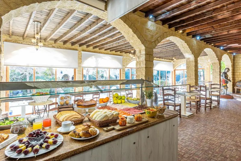 Un buffet propose des fruits, des viennoiseries et des pâtisseries dans une salle à manger lumineuse.