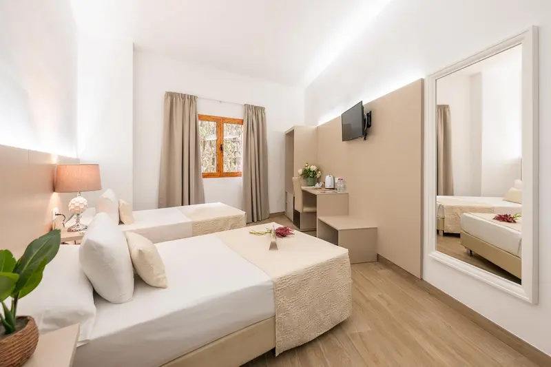 Chambre lumineuse avec deux lits simples et un grand miroir.