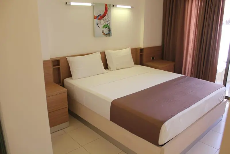 Une chambre lumineuse avec un grand lit recouvert d'une courtepointe.