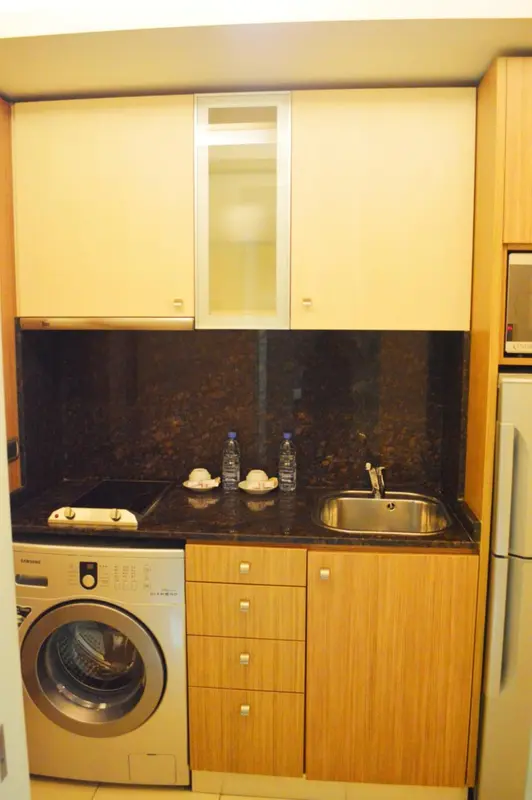 Une kitchenette avec un évier, des rangements et un électroménager.