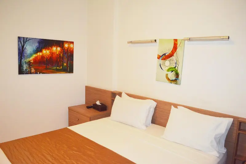 Une chambre avec un lit double et des tableaux décoratifs au mur.